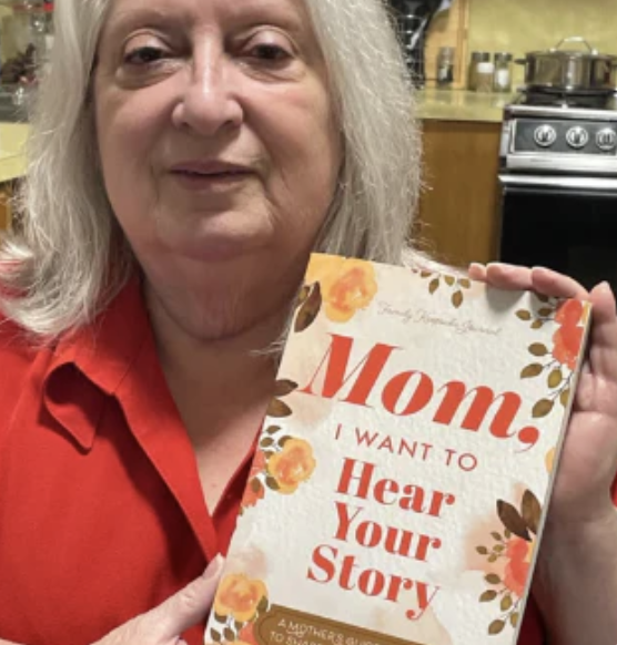 Happy mother holding Tell Tales Mom journal